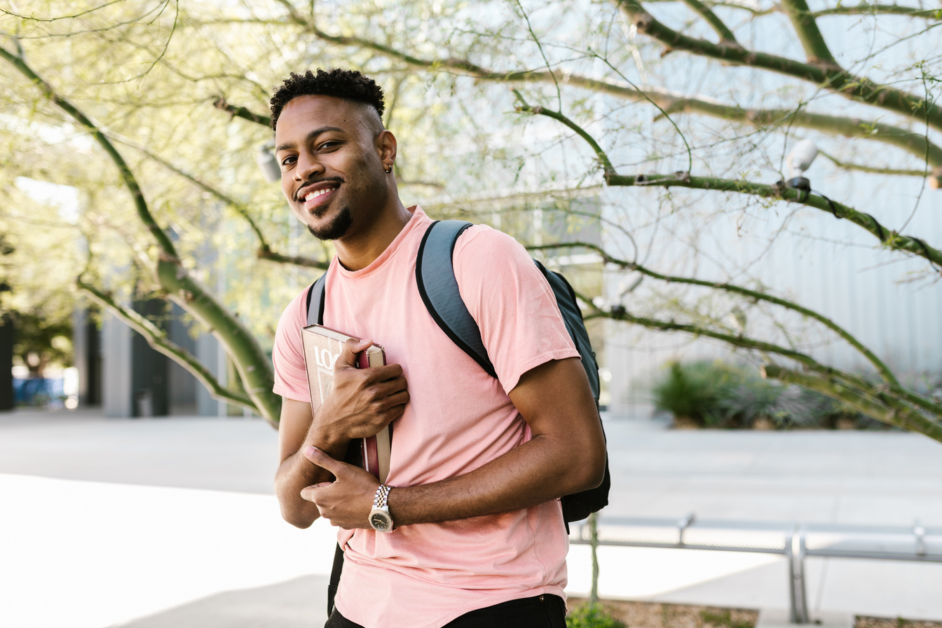 A College Student Holding a Book and Smiling